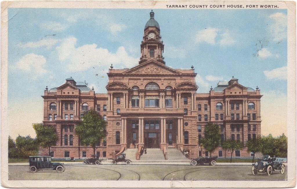 A vintage color postcard showing a large ornate courthouse building with a central clock tower, trees, steps, and several early automobiles; text at the top